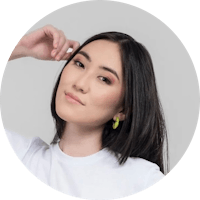 a woman wearing a white t - shirt and green earrings